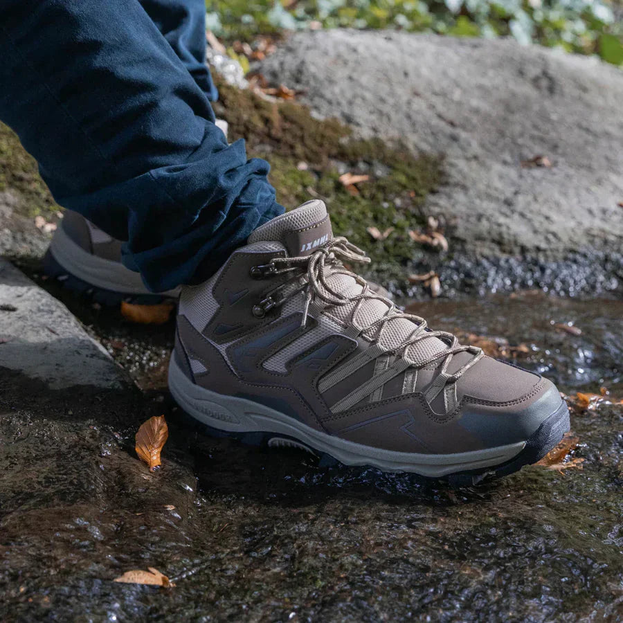Person wearing a hiking boot on a rocky surface with water
