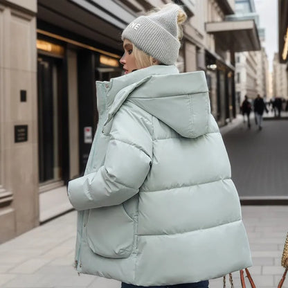 Person wearing a light blue puffer jacket and gray beanie on a city street.