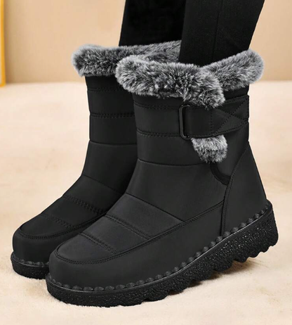 Black snow boots with gray fur trim on a beige background