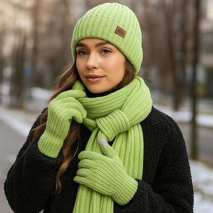 Woman wearing a green knit hat, scarf, and gloves in a snowy outdoor setting.