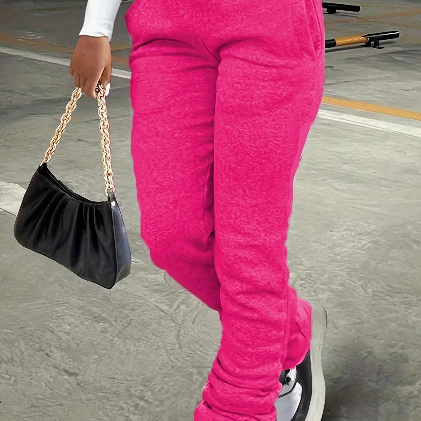 Person wearing bright pink pants and holding a black handbag with a gold chain.