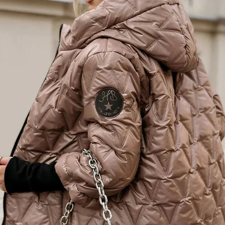 Close-up of a person wearing a brown quilted jacket with a brand logo on the chest.