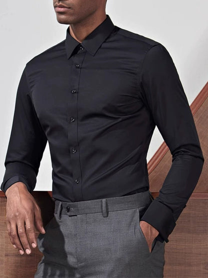 Person wearing a black dress shirt and gray pants against a neutral background