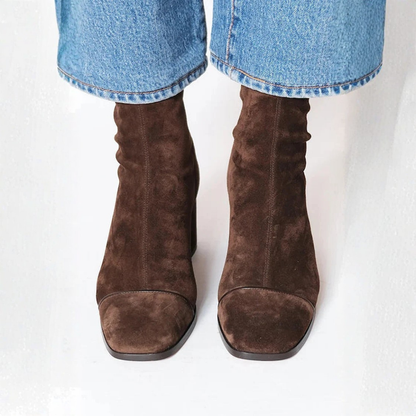 Brown suede boots worn with blue jeans on a white background