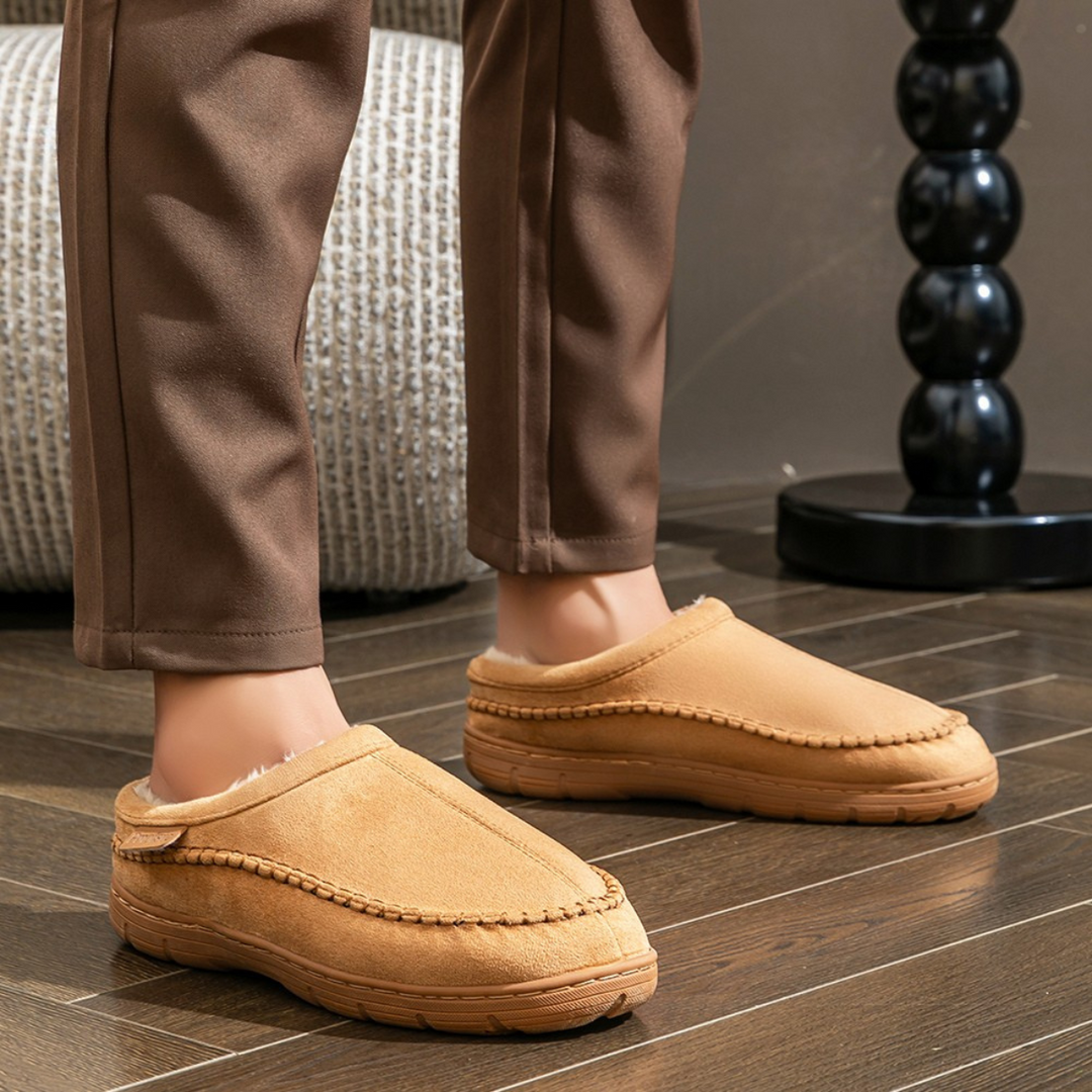 Brown slippers worn indoors on a wooden floor.