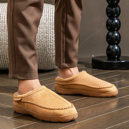 Brown slippers worn indoors on a wooden floor.