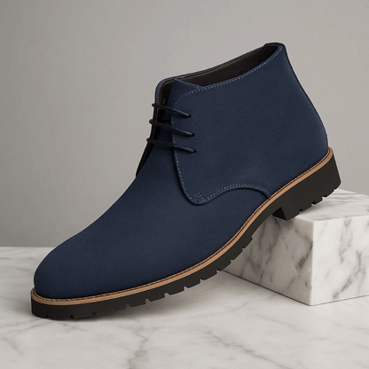 Navy blue chukka boot with brown trim on a marble surface