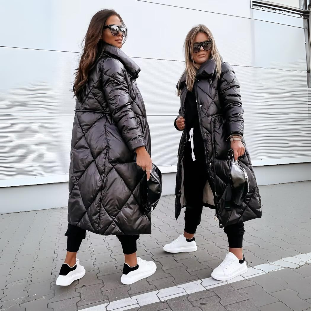 Two women wearing long black puffer coats in an urban setting.
