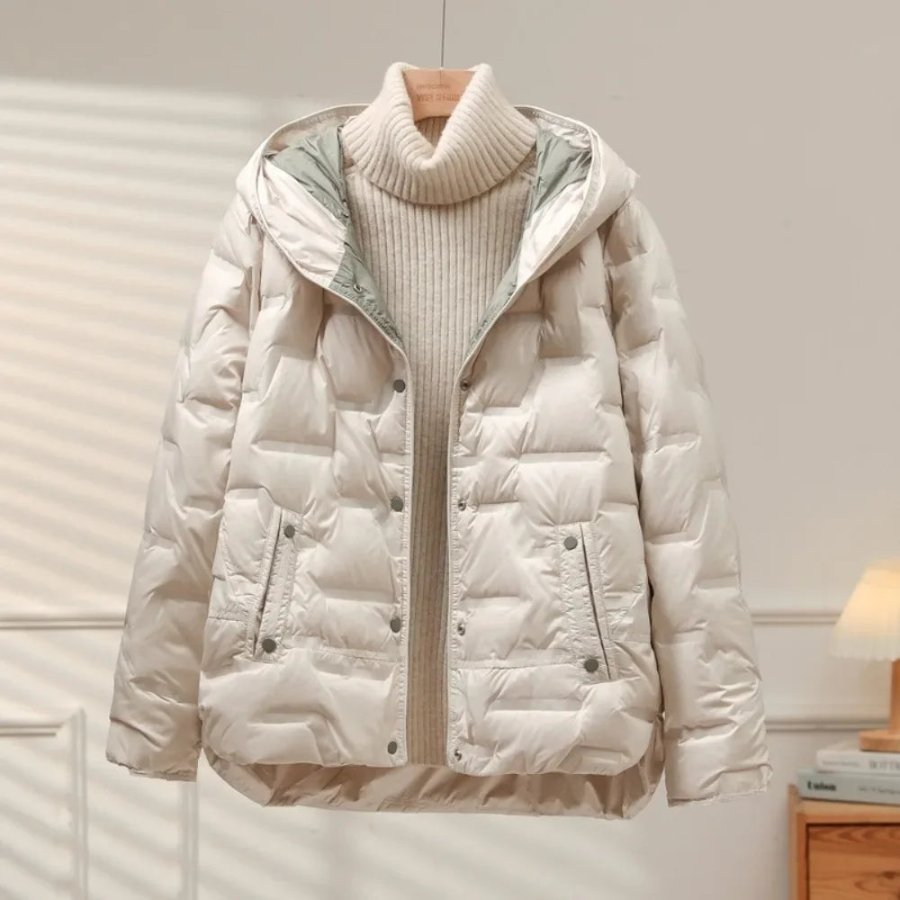 White puffer jacket with a beige sweater underneath on a wooden hanger against a neutral background.