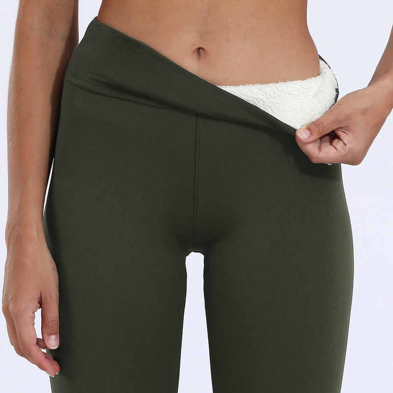 Green leggings with white lining being adjusted on a person against a light gray background