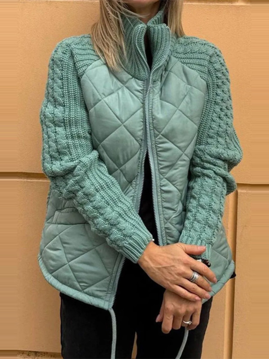 Teal quilted jacket with cable knit sleeves against a beige wall