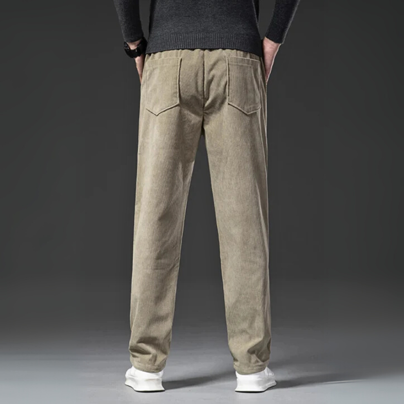 Beige corduroy pants worn by a person on a gray background