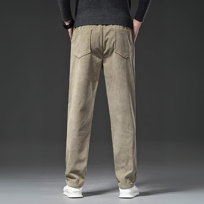 Beige corduroy pants worn by a person on a gray background