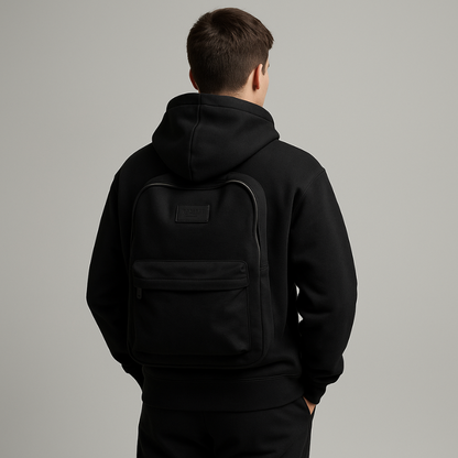 Person wearing a black hoodie with a backpack on a gray background