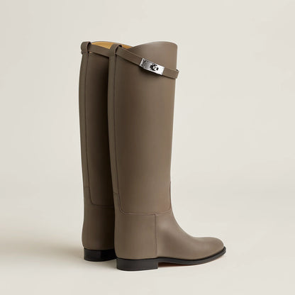 Pair of brown knee-high boots with a strap on a beige background