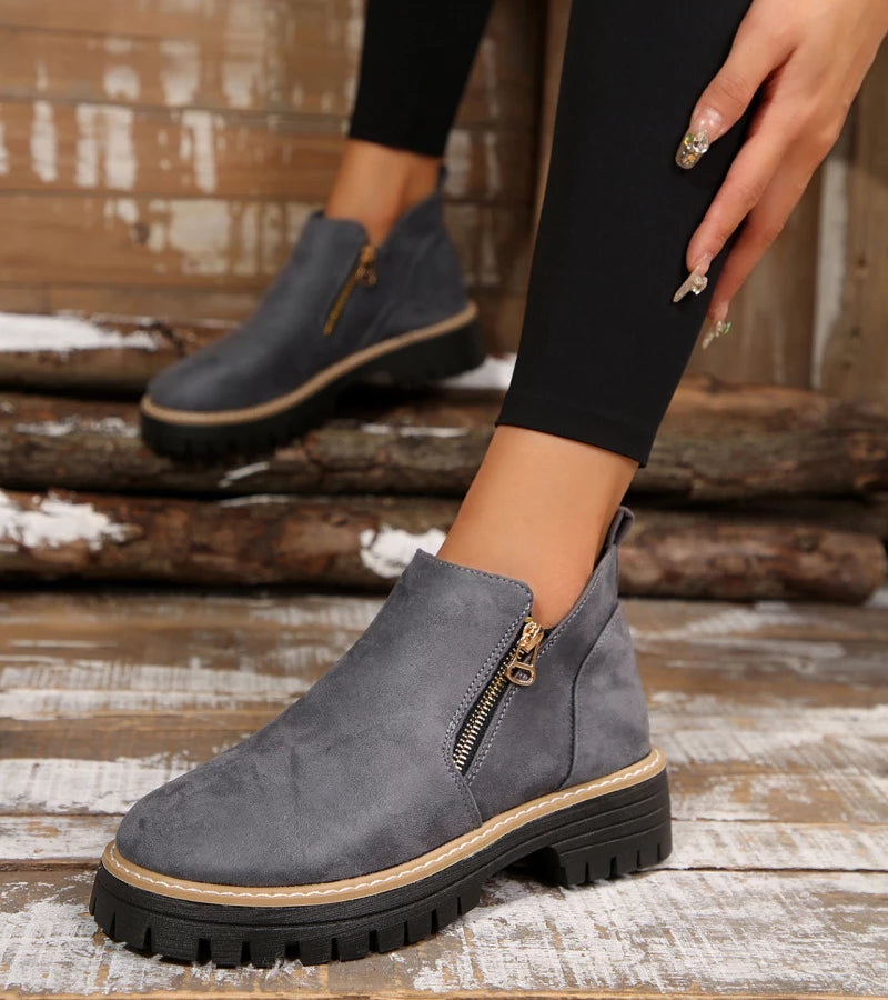 Gray ankle boots with a zipper on a wooden floor.