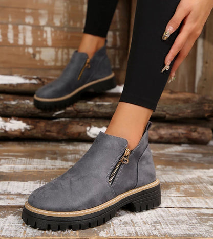Gray ankle boots with a zipper on a wooden floor.