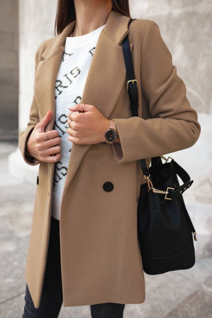 Person wearing a beige coat with a black handbag on a blurred street background