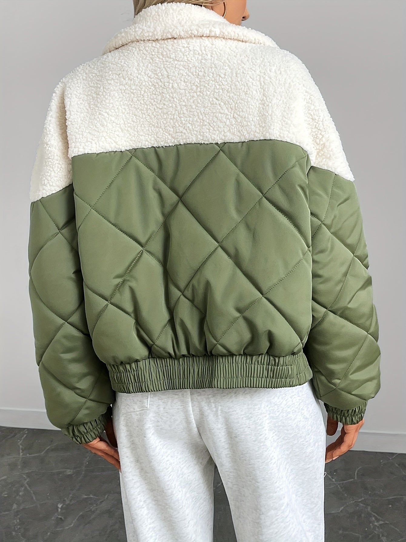 Green quilted jacket with white collar worn by a person on a gray background