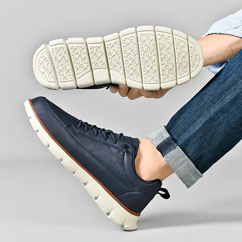 Person wearing navy blue sneakers with white soles, holding one shoe to show sole texture.