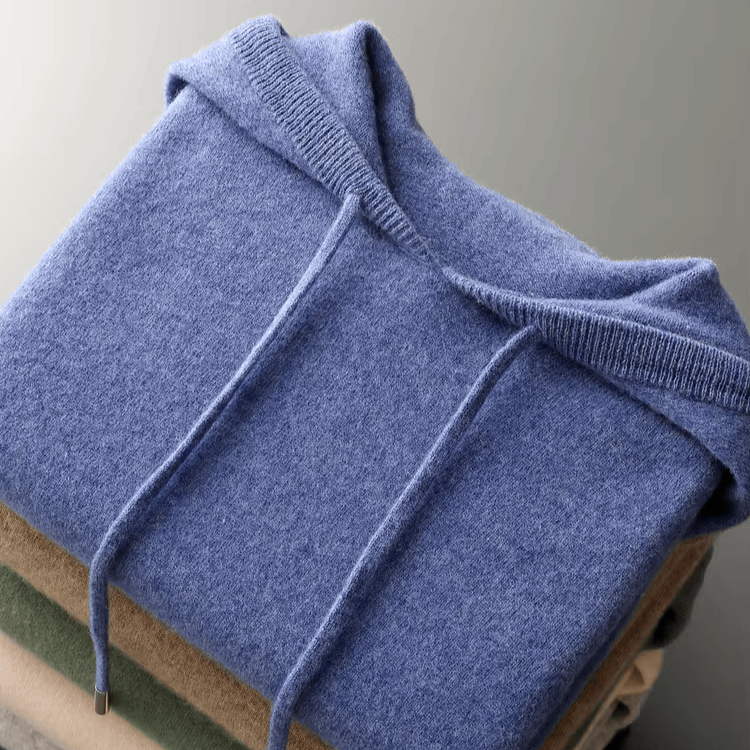Folded blue sweater on a wooden surface with a neutral background