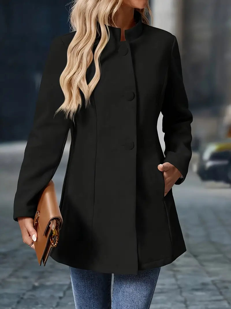 Person wearing a black coat holding a brown clutch on a blurred street background