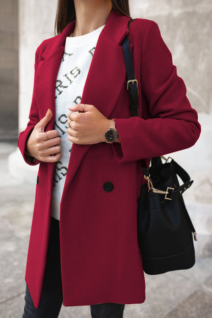 Person wearing a red coat with a black handbag, standing against a neutral background