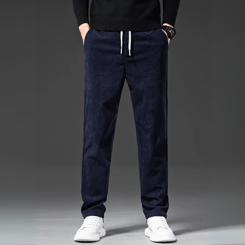 Navy blue jogger pants worn by a person on a gray background
