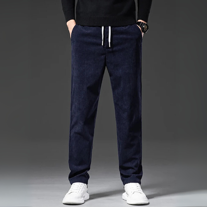 Navy blue jogger pants worn by a person on a gray background