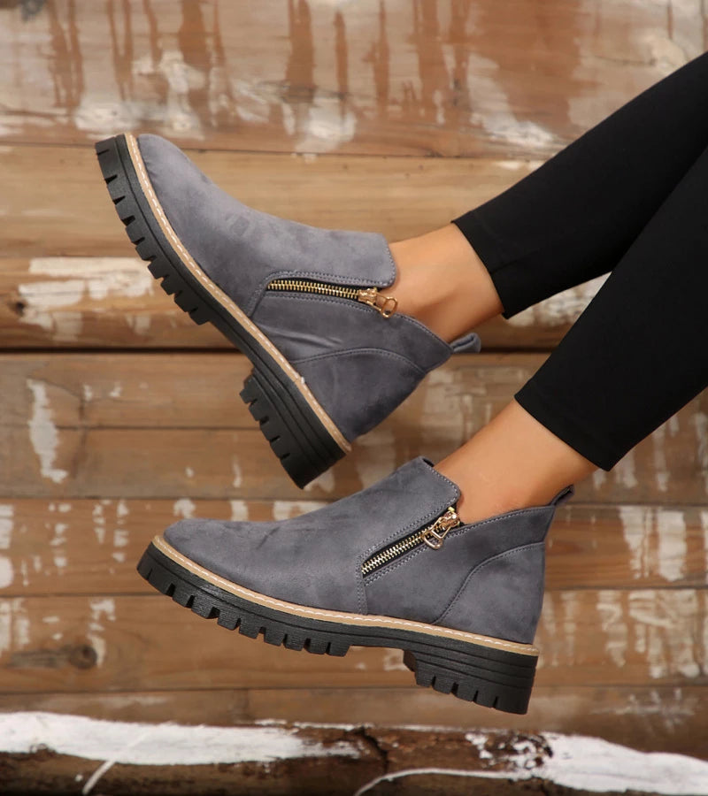 Gray ankle boots with zippers on a wooden floor