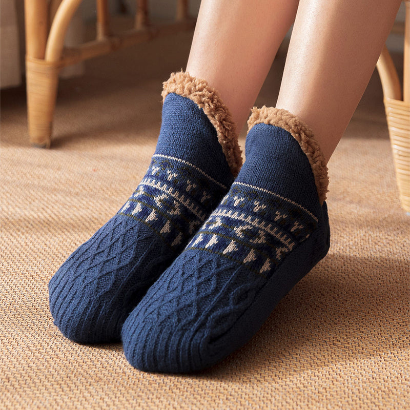 Blue knitted socks with brown fuzzy trim worn by a person on a beige carpet.