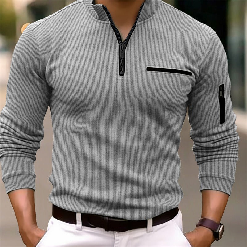 Gray ribbed sweater with black zipper and pocket details on a blurred background