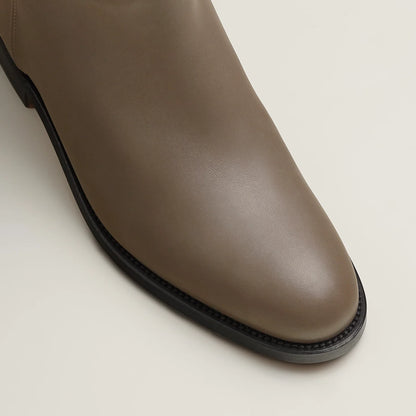 Brown leather boot on a light beige background