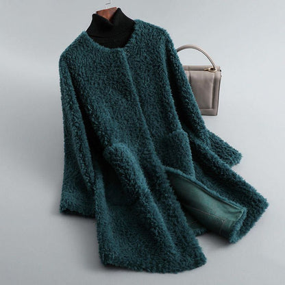 Teal fuzzy coat draped over a hanger with a gray handbag on a light gray background