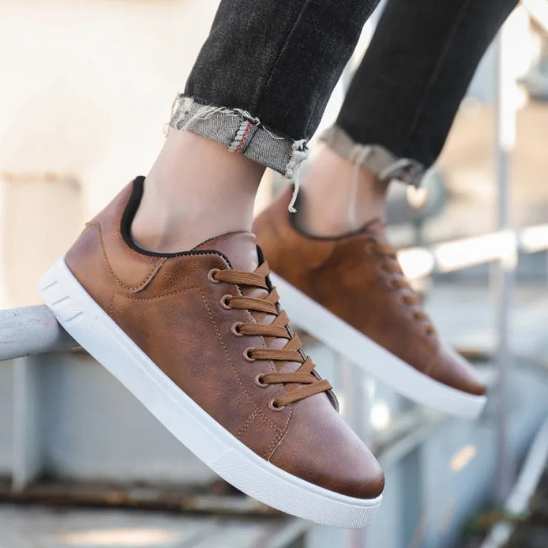 Brown sneakers with white soles worn by a person sitting on a metal railing.