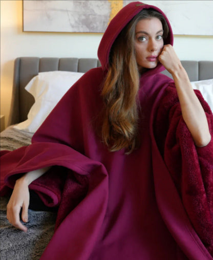 Woman wearing a burgundy hooded blanket in a bedroom setting