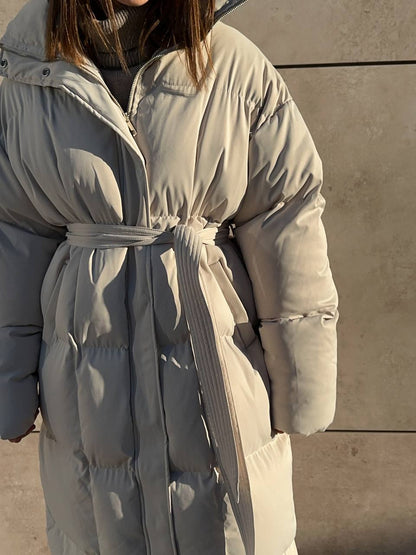 Person wearing a light gray puffer coat against a neutral background