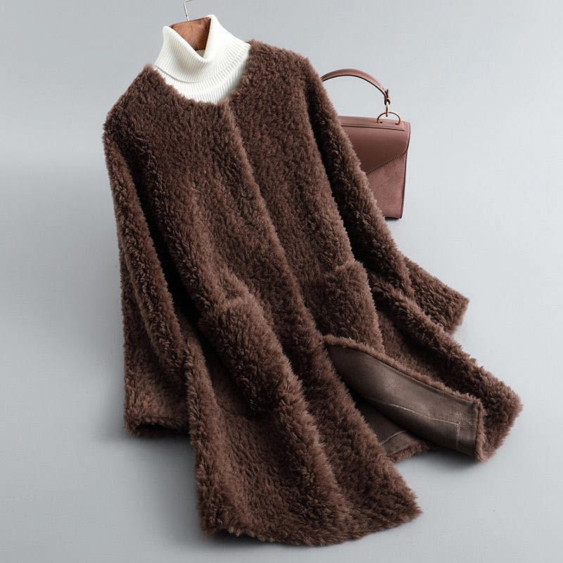 Brown fluffy cardigan on a hanger with a white turtleneck sweater and brown handbag on a light gray background