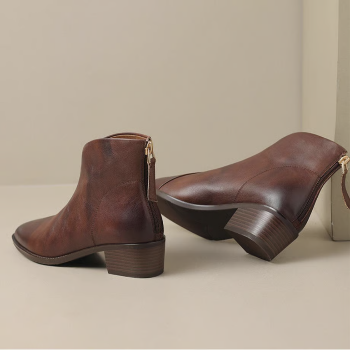 Pair of brown leather ankle boots on a beige background