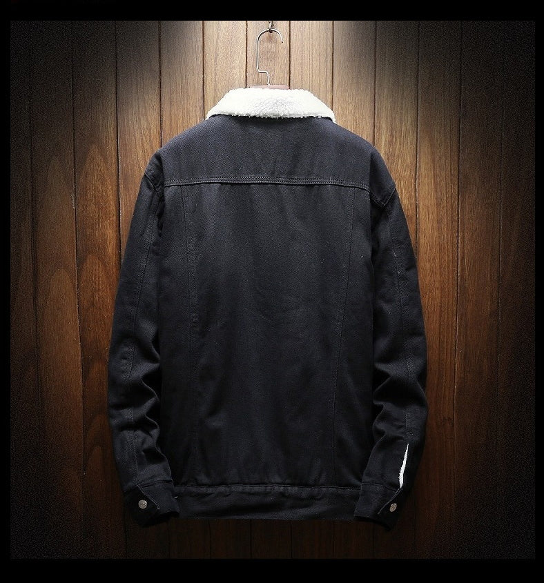 Black jacket with white collar on a wooden hanger against a wooden wall.