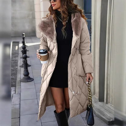 Woman in a long beige coat with fur hood, holding a coffee cup and a handbag, walking outdoors.
