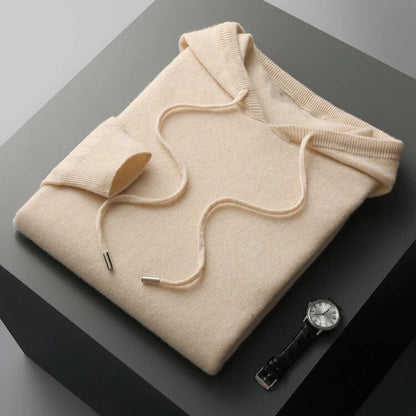Folded beige hoodie on a dark surface with a watch