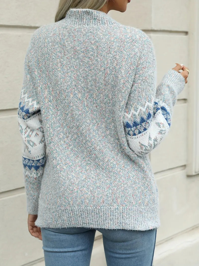 Person wearing a light blue sweater with patterned sleeves against a neutral background