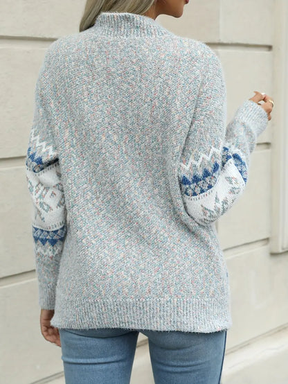 Person wearing a light blue sweater with patterned sleeves against a neutral background