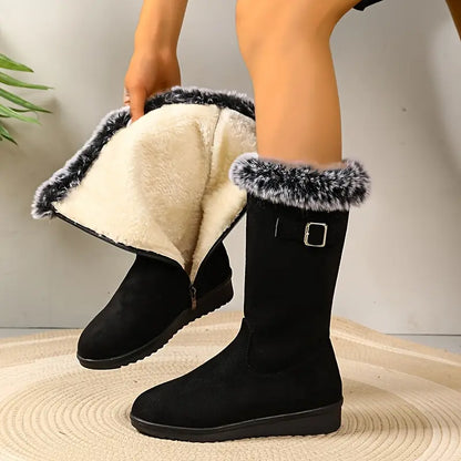 Black winter boots with fur trim worn by a person on a neutral background