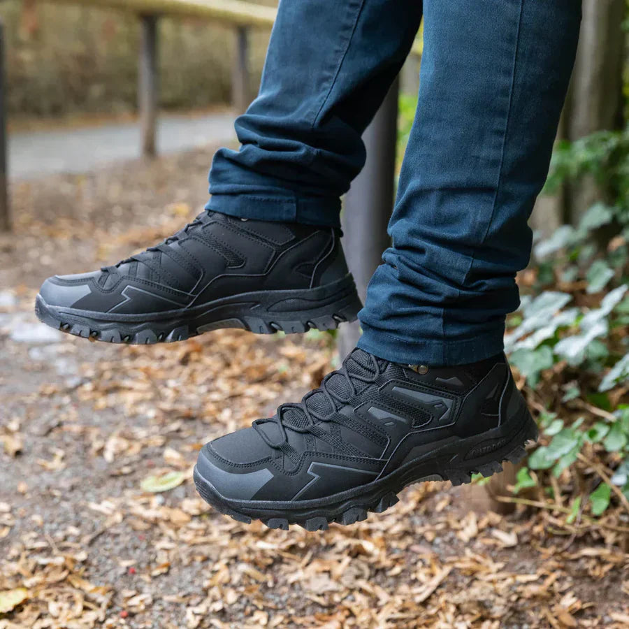 Black hiking boots worn with blue jeans on a natural background