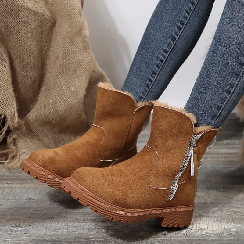 Brown suede ankle boots with fur lining worn with blue jeans on a wooden floor.