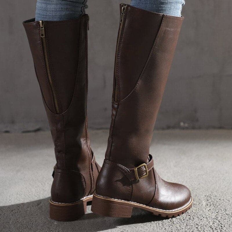 Brown knee-high boots with a buckle on a neutral background