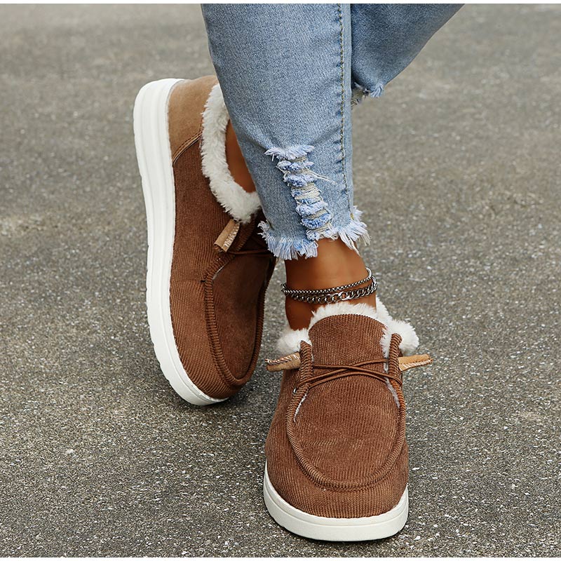 Brown suede shoes with white soles worn with ripped jeans on a concrete surface