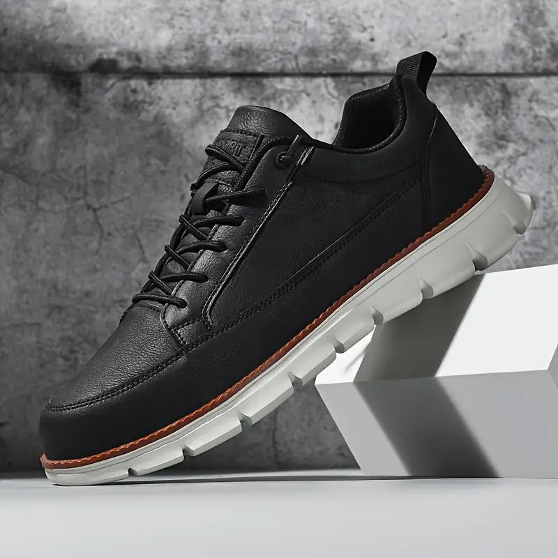 Black leather sneaker with white sole on a gray background
